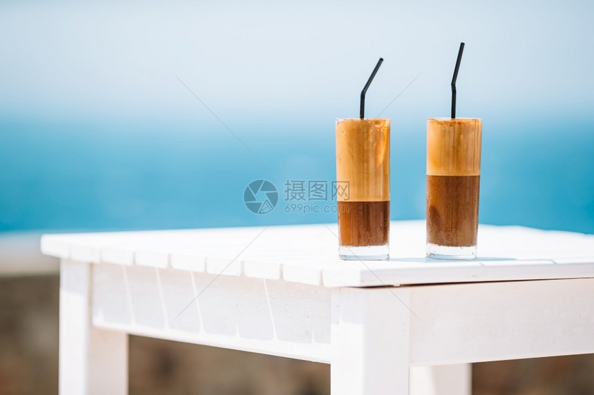 冰沙凉爽的早晨冷咖啡拿铁在有海背景的木制桌上咖啡拿铁在有海背景的木制桌子上图片