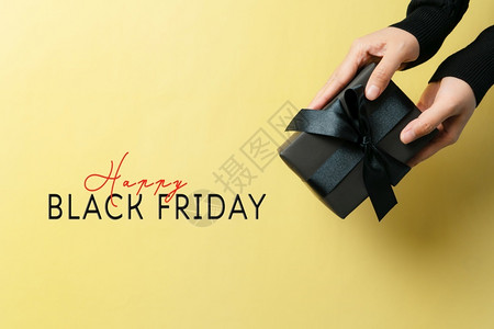 零售网站行业黑色周日售卖女人用黄色背景的礼物盒给女人手图片