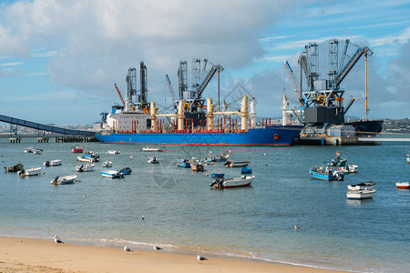 可逆的海岸油质的葡萄牙特拉法里亚的粮食衍生产品和油质的深水码头和筒仓在海滩附近有渔船葡萄牙特拉法里亚的粮食衍生产品和油质的深水码头和筒背景