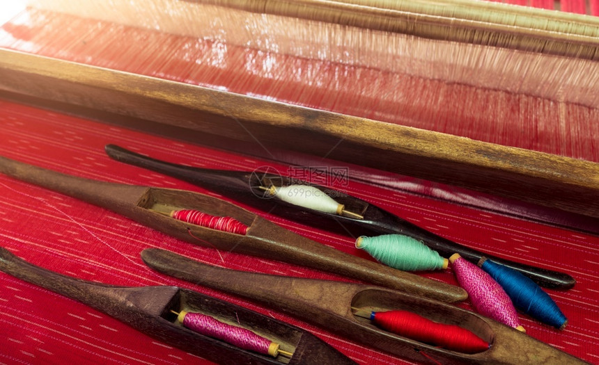 有选择地侧重于编织机上器的穿梭工具中的红色粉蓝绿的丝线使用传统的编织和纺或布的生产蓝色可选择木制图片