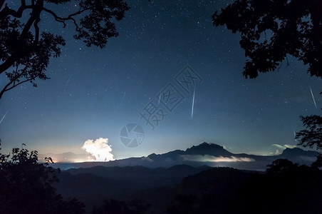 英仙座夜空中山脉上的流星雨设计图片