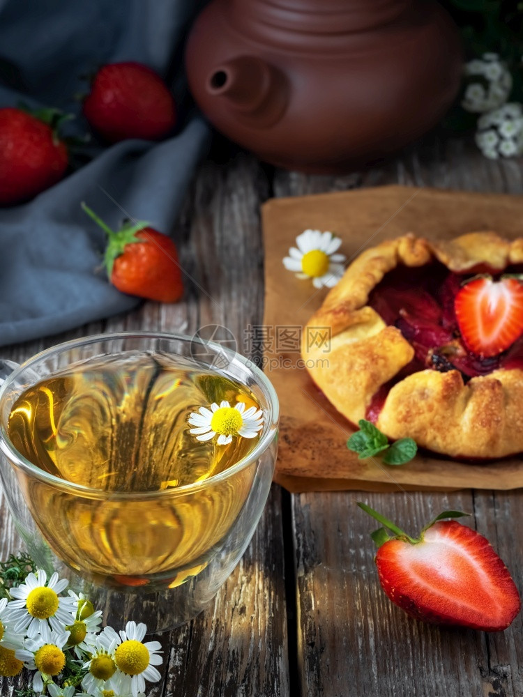 烘烤新鲜面包卷饼或桌上开张的草莓派关闭自制蛋糕新鲜果子和一杯甘菊茶食物脆皮图片
