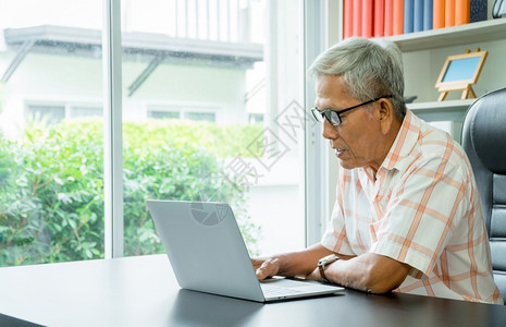 使用笔记本电脑计算和录日常开支的亚洲快乐老人生活方式学习和金融业务概念a生活学习和金融业年长的桌子制作背景图片