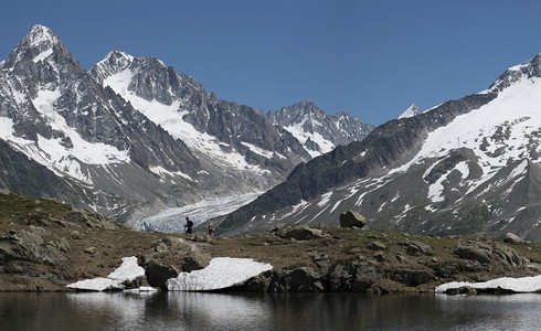 高的人们在山上一个湖边徒步旅行其背景是冰川和池塘小路图片