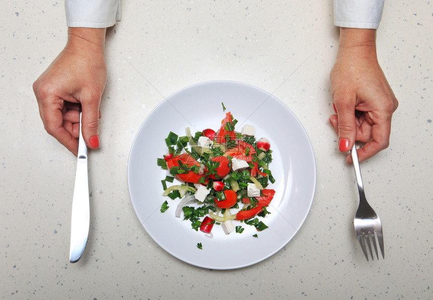 吃餐具和新鲜蔬菜被切成白色板块并用手握着厨房的平板家具和新鲜蔬菜饮食长牙的图片