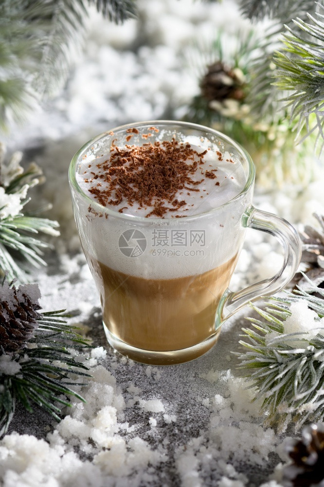 摩卡可新的在雪覆盖松树枝和雪中一杯大热咖啡加巧克力剃须还有巧克力刮胡屑图片