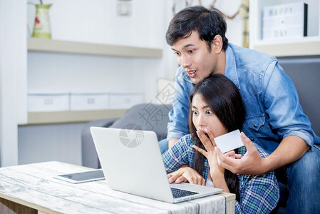 购买网络信用使笔记本电脑的家庭概念恋人技术时爱人是令惊讶的欢呼高清图片素材