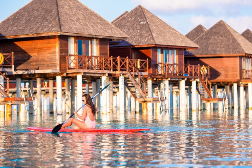 夏天湿的水女在马尔代夫海上冲浪活跃的年轻女子站在桨板上立图片