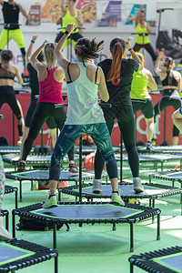 飞跃迷你Rebounder锻炼女孩在健身房课堂上与音乐和老师在舞台上进行健身锻炼迷你女孩在健身房课堂上与音乐和老师在舞台上进行健背景