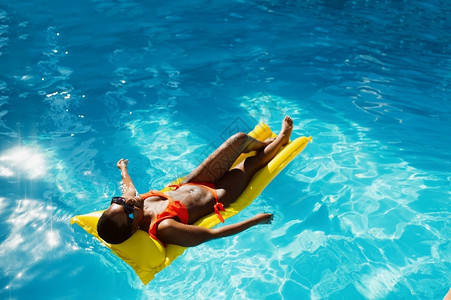 泳衣女人躺在游泳池的气垫上图片