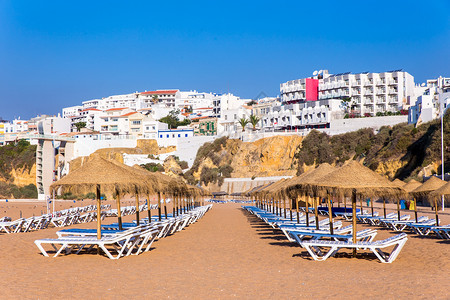 带白色建筑物和蓝天空的海滩阳伞行水岸游客背景图片