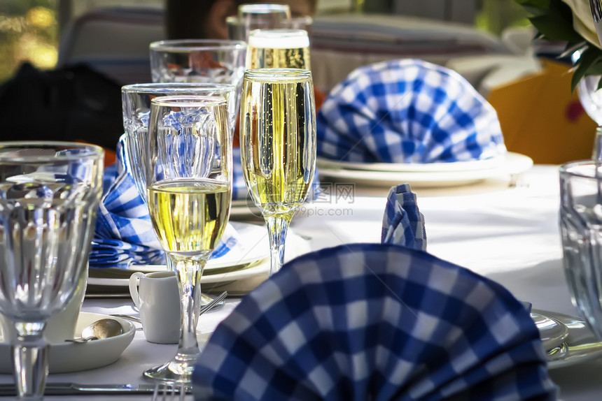 香槟酒散焦餐厅在节日装饰的桌子上用白色和蓝餐巾纸杯香槟子在桌上有白和蓝色餐巾纸突出玻璃杯香槟图片