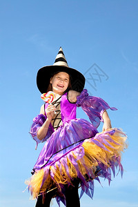 可爱的情感小姑娘在蓝天舔花朵糖果的歌剧中情绪化帽子俏皮图片