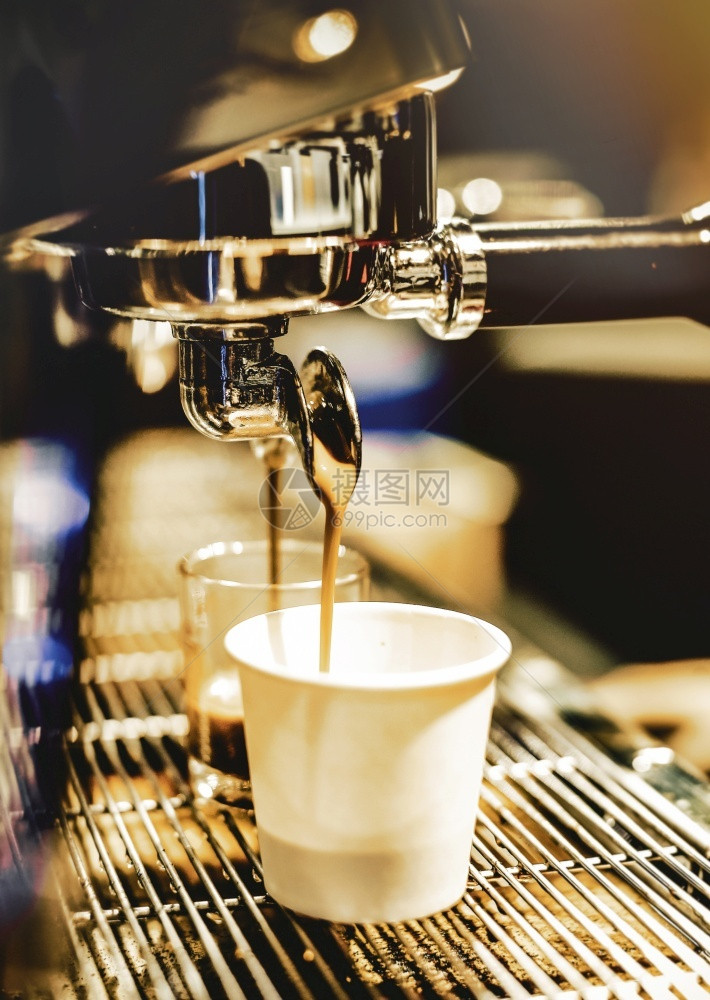 温暖的香气热浓缩咖啡机冲泡倒入店的玻璃杯中浓缩咖啡从机中倒出图片