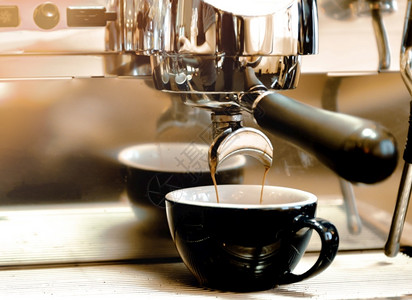 填充早餐自动的浓缩咖啡机冲泡倒入店的玻璃杯中浓缩咖啡从机中倒出图片