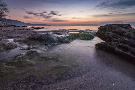 日出前惊人的宁静海和岩石岸预期平支撑图片