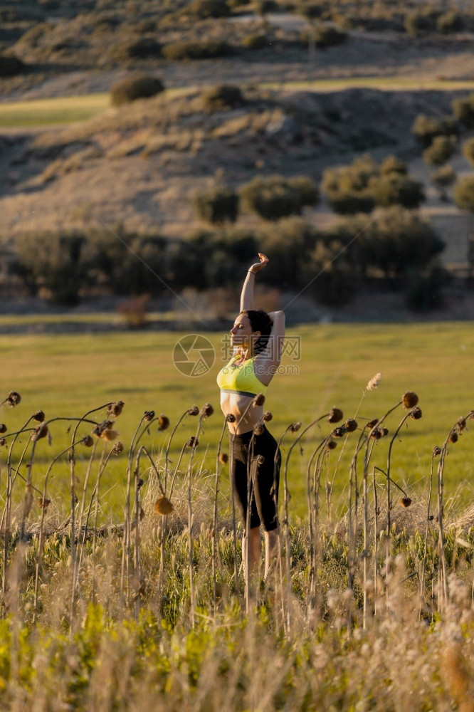 身体植物拉伸穿运动服的布朗特妇女穿着运动服用手臂伸展运动同时在农村布鲁奈特妇女在运动服中工作一边用胳膊伸展运动一边锻炼图片