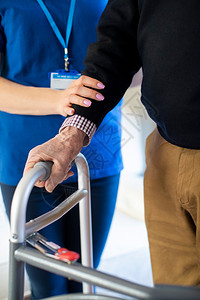 成人由护理工作者帮助的用手走着框架的近身老人关怀无效的图片
