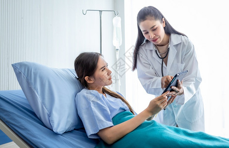 医生用平板电脑向年轻女患者讲解病情背景图片