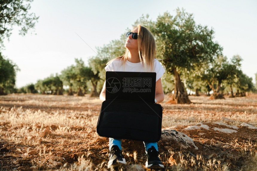 训练农作物坐在橄榄树田里的拥有笔记本电脑的年轻妇女案子图片