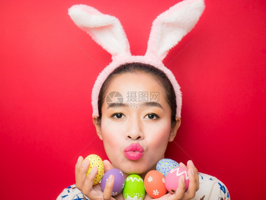 假期裙子手复活节时戴兔子耳朵头带和携复活节鸡蛋的妇女有吸引力的年轻女微笑在明亮的红色背景上笑图片