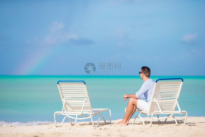 男人海滩上的年轻独自在日光浴床上休息海滩的年轻人独自在户外的日光浴床上休息独自的图片