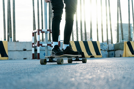 轮子所有者无法辨认的女人骑着长板在日光公园周围滑板运动图片