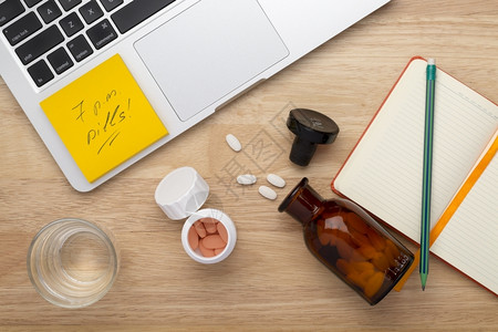 霍鲁任科笔记本电脑在线治疗抗应激反概念桌上摆有瓶药丸的子片在线治疗概念木制桌子上摆有瓶药片痛止背景