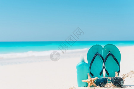 吸引人的景观热带白色沙滩背景海洋上的触发器防晒霜瓶护目镜海星和太阳白色沙滩背景海洋上的防晒霜瓶海星和太阳镜背景图片