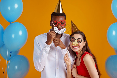 人们盖帽戴子和派对面具的风趣情侣黄色背景漂亮的家庭活动或生日庆典气球装饰oopicapi图片