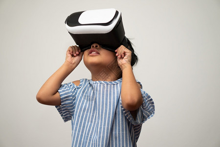 拥有虚拟现实头盔的亚洲小女孩对于新体验3D小玩意技术概念虚拟世界小玩具游戏及未来在线教育说令人兴奋ieminform耳机未来派可背景