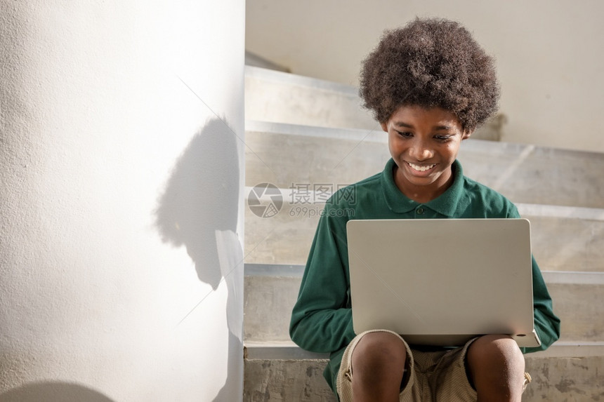 新冠一名非洲卷发男孩坐在楼下走廊一栋的台笔记本电脑上联系非洲人图片