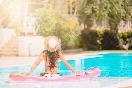 泳装美少女马尔代夫穿比基尼的姑娘在豪华酒店户外泳池里美少女在游泳池里放松她正在游泳池里放轻松床垫田园诗般的背景