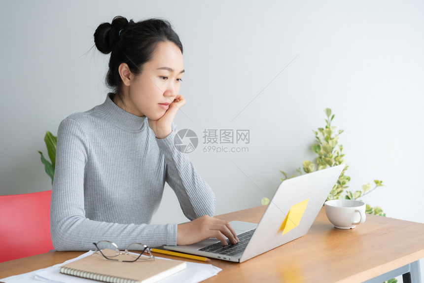 办公室年轻女在主办公桌做笔记本电脑工作坐在桌子上手靠着下巴躺工人在职的图片