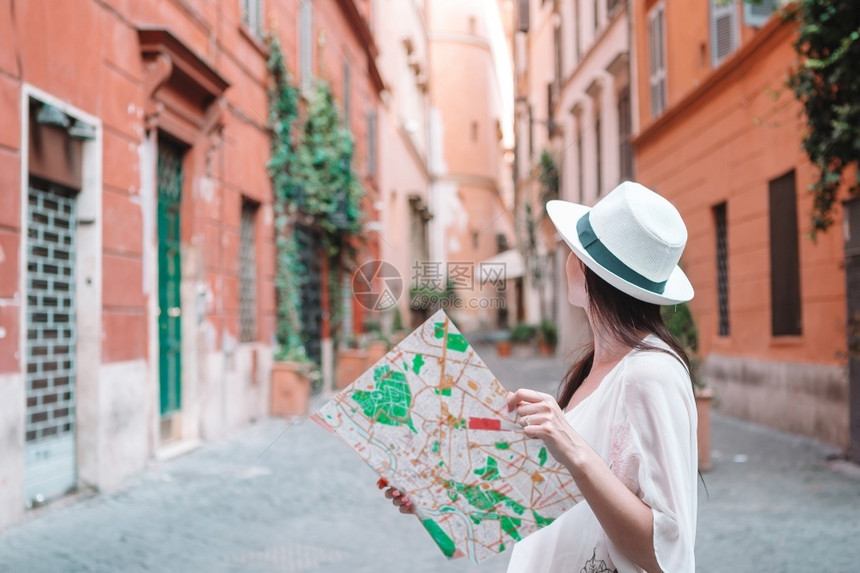 古老的快乐年轻女子在欧洲的意大利老街上拿着城市在意大利度假期间在罗马的户外旅游妇女带着在欧洲度假期间布拉格户外带着的旅游妇女帽子图片