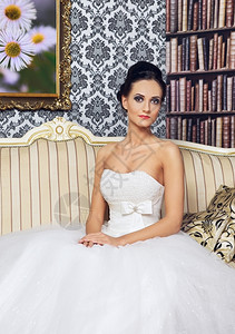 坐在沙发上穿着婚纱的美丽新娘年轻女士优雅的复古完美图片