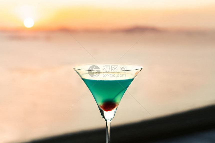 蓝鸡尾酒和樱桃在日落的窗外美丽庆祝红色图片