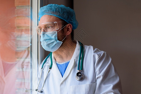 戴口罩看向窗外的男医生背景图片