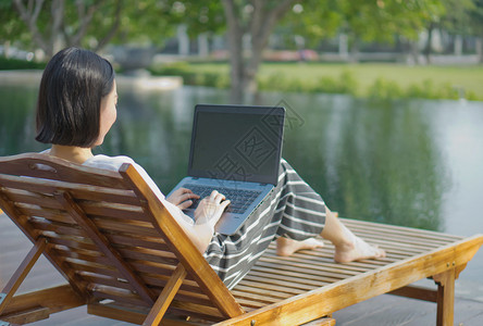 白色的国外游泳在池旁使用膝上型计算机的妇女图片