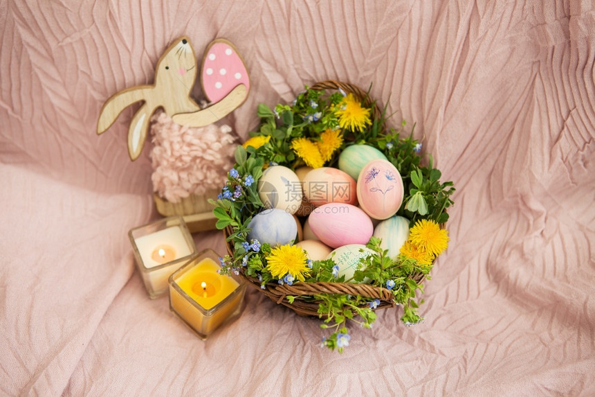 看在柔和的床罩上是一篮草和各种鲜艳的花朵一只兔子篮里有复活节彩蛋上面涂有美丽柔和的水彩画在柔和的床罩上是一篮草和各种鲜艳的花朵一图片