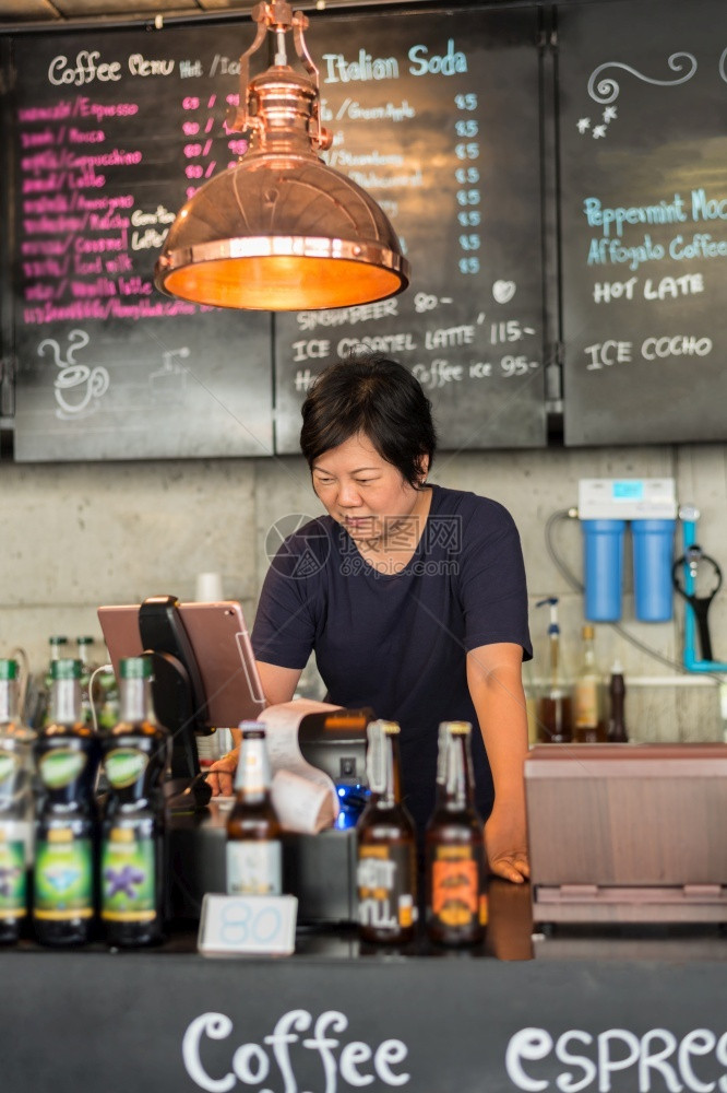 亚洲40多具白皮卷发体是咖啡店老板向馆厅的顾客提供出纳服务亚洲女在咖啡店提供出纳服务工人咖啡屋里面图片
