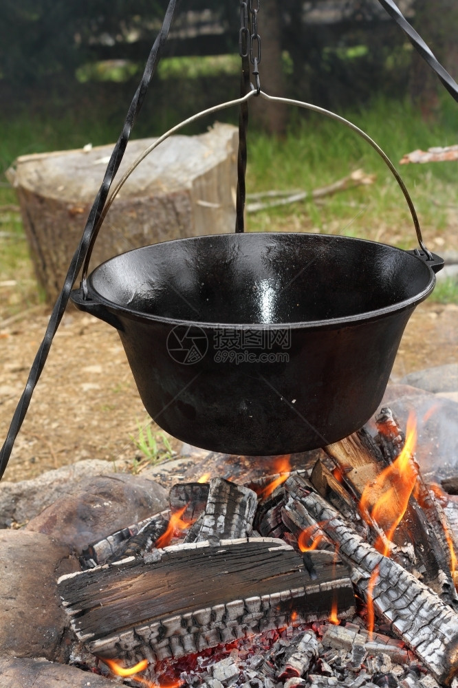 荒野用古老的代金属锅炉老旧的黑大烧营火时做烹饪焰温暖的图片