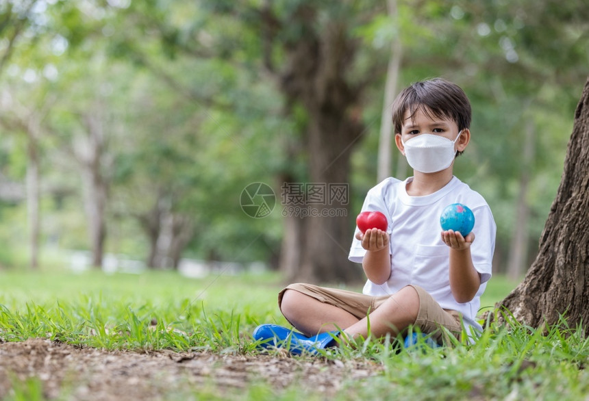 水流行病生长男孩戴面罩防止污染手握着一个地球和心脏看着照相机爱健康地球概念a爱健康地球概念图片