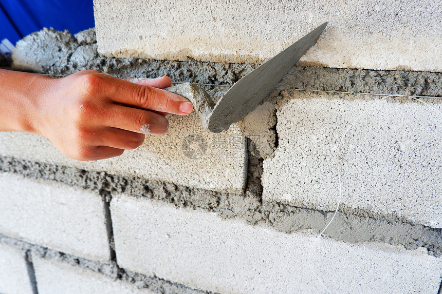 技术砂浆砖匠手在用水泥块建造墙壁上工作并使用水泥砖块石工图片