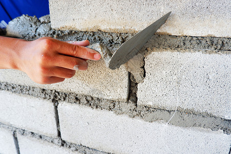 技术砂浆砖匠手在用水泥块建造墙壁上工作并使用水泥砖块石工图片