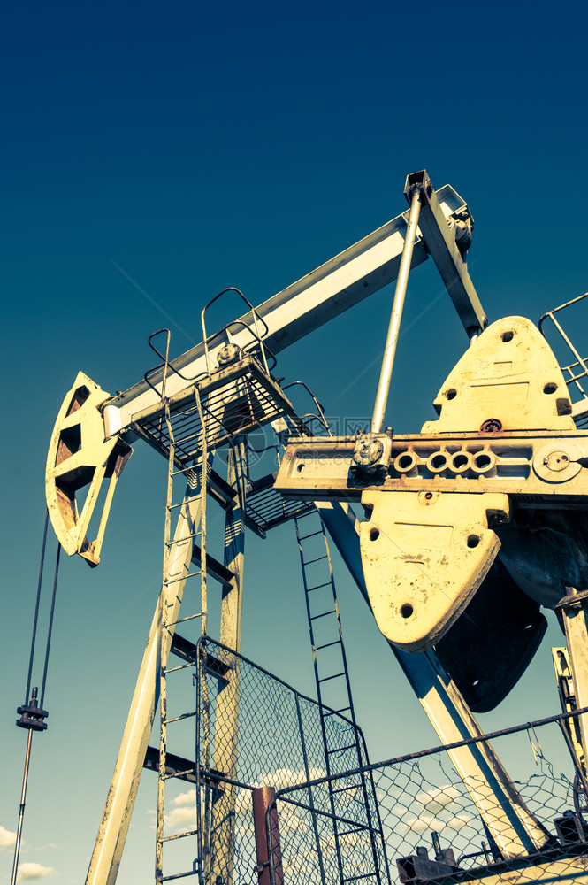 重的商业自然油泵在日落天空背景的工业设备用于提取石油的摇摆机采矿石油概念泵工业设备图片