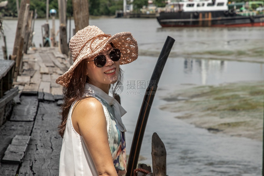 夏天地标女士穿着临时服装的女孩在河边旧木头码上欢笑着坐个人假日图片