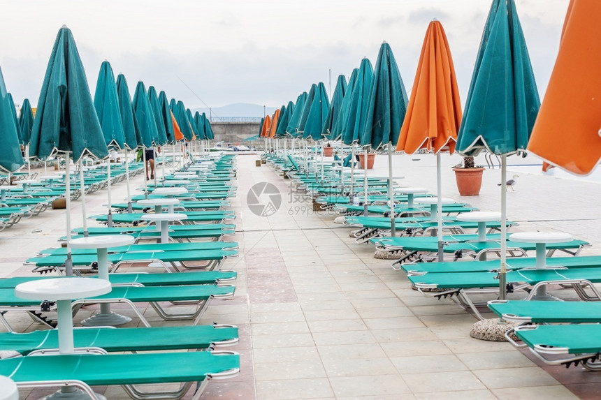 保加利亚杜尼暑假度胜地游泳池附近的绿色和橙雨伞太阳床保加利亚杜尼椅子靠近甲板图片