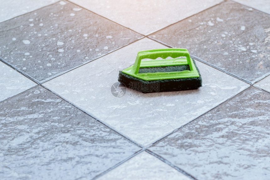 关闭一个绿色塑料刷子用于洗涤和清洁放在湿瓦式地板上的建造卫生家图片