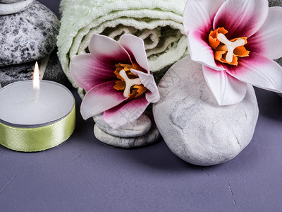 设置温泉的一块石头毛巾燃烧蜡烛和花朵用石头蜡烛兰花装饰反射排精神图片